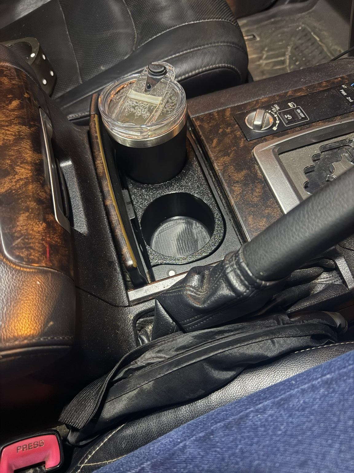 Cup holder insert installed in a woodgrain 200 Series centre console