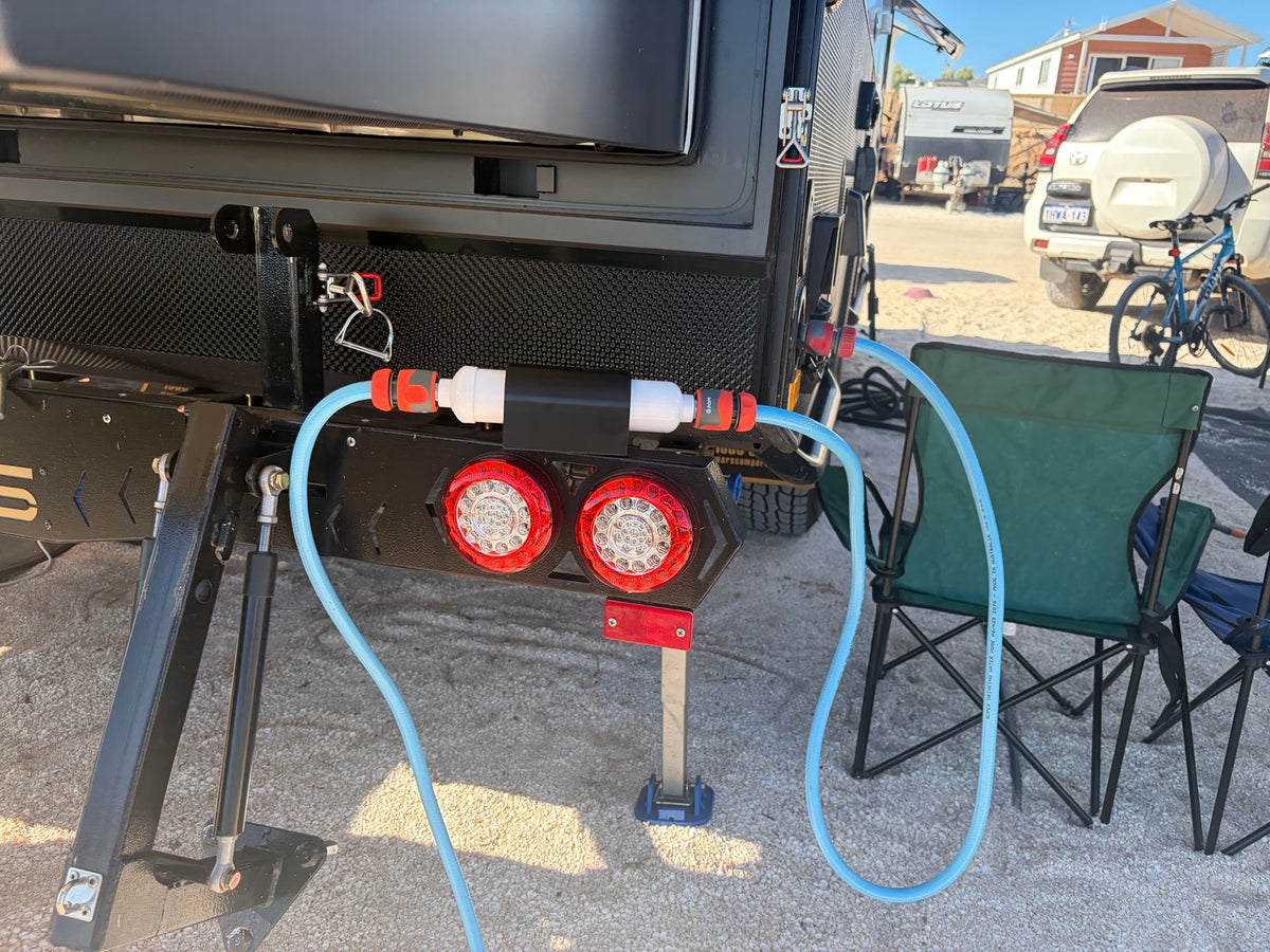Hybrid Prints magnetic inline water filter holder installed on a caravan at a campsite